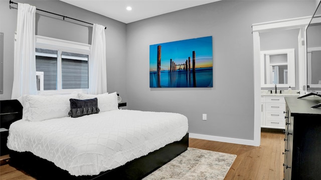 bedroom with ensuite bath, light hardwood / wood-style flooring, and sink