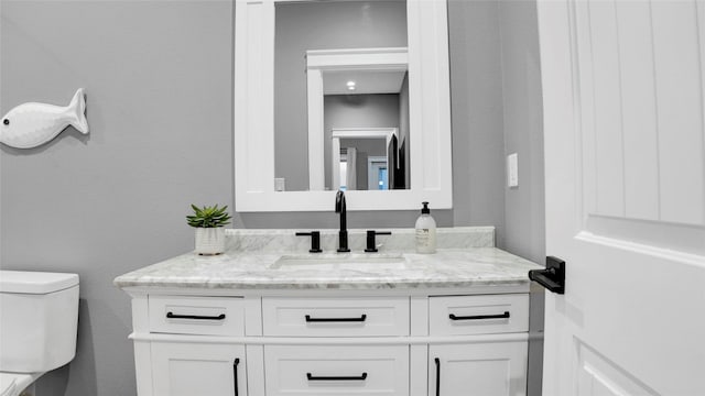 bathroom featuring a textured wall, vanity, and toilet