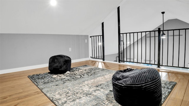 living area featuring baseboards, vaulted ceiling, and wood finished floors