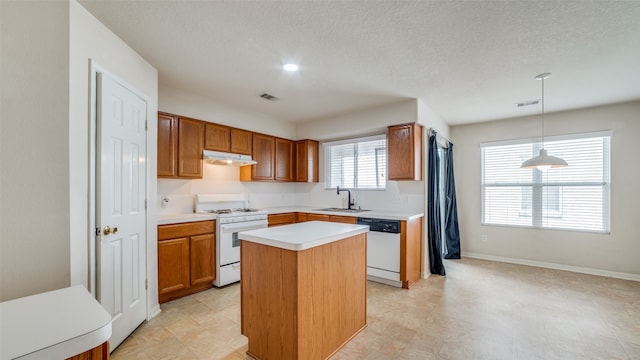 kitchen featuring a textured ceiling, a kitchen island, white appliances, pendant lighting, and sink