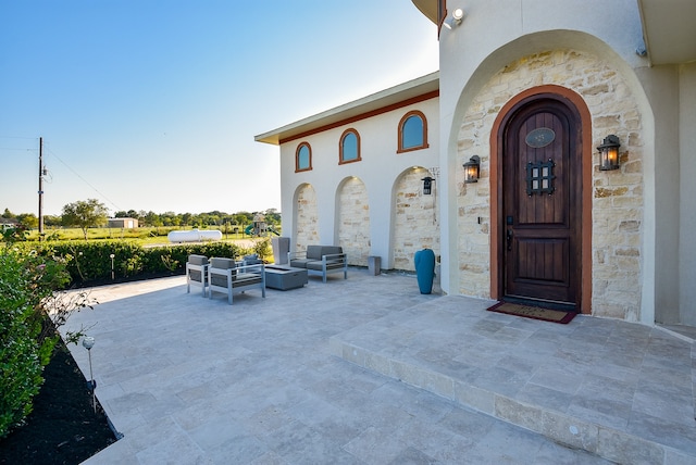 entrance to property featuring an outdoor living space and a patio area