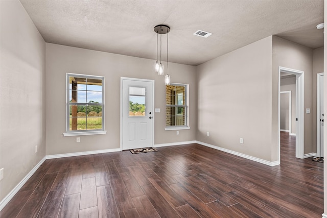 foyer entrance featuring a textured ceiling and dark hardwood / wood-style floors