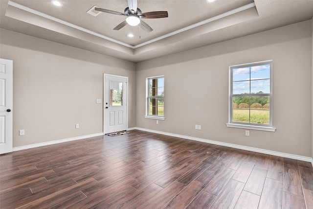 unfurnished room featuring ornamental molding, a raised ceiling, dark wood-type flooring, and ceiling fan