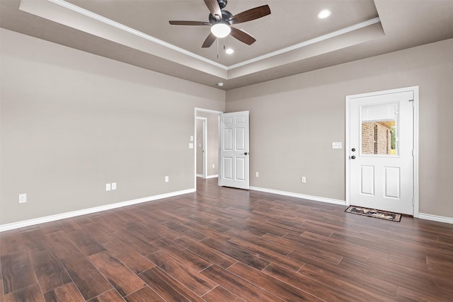 spare room with dark wood-type flooring, ceiling fan, ornamental molding, and a tray ceiling