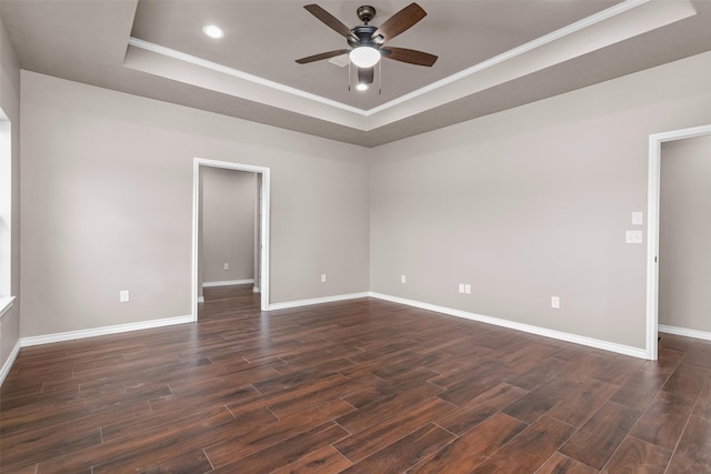 spare room featuring ornamental molding, dark wood-type flooring, a raised ceiling, and ceiling fan