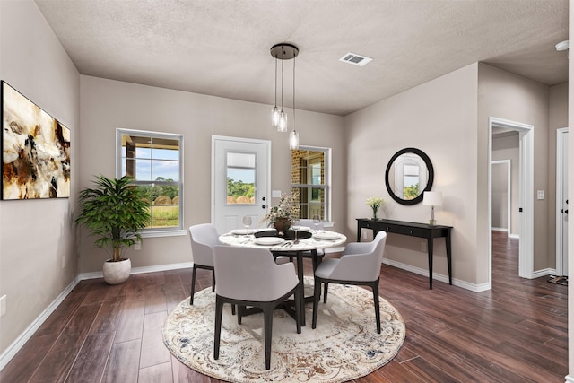 dining room featuring a textured ceiling and dark hardwood / wood-style floors