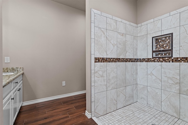 bathroom with hardwood / wood-style floors, tiled shower, and vanity