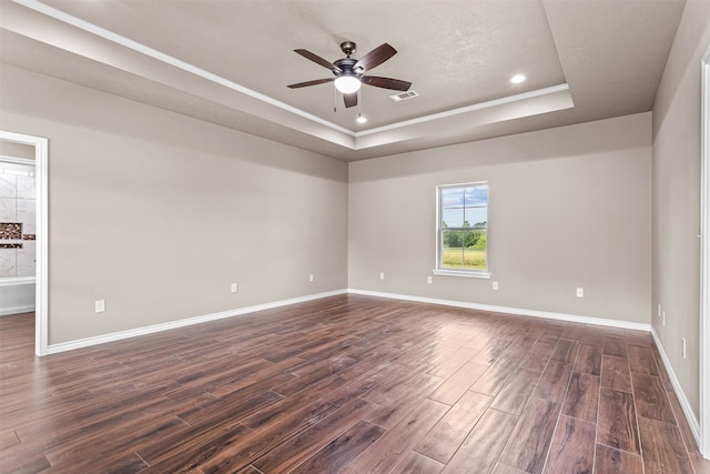 spare room featuring a raised ceiling, dark hardwood / wood-style flooring, and ceiling fan