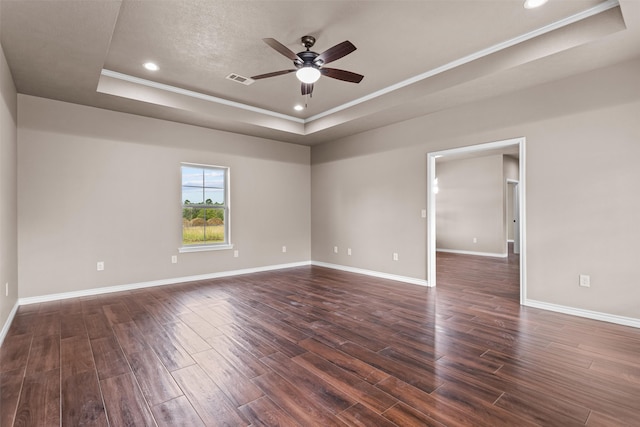 unfurnished room featuring crown molding, a textured ceiling, ceiling fan, dark hardwood / wood-style floors, and a tray ceiling