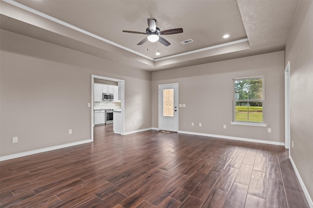 spare room with a tray ceiling, ornamental molding, ceiling fan, and dark hardwood / wood-style floors