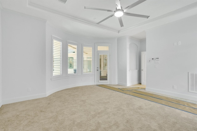 spare room with a raised ceiling, light colored carpet, and ceiling fan