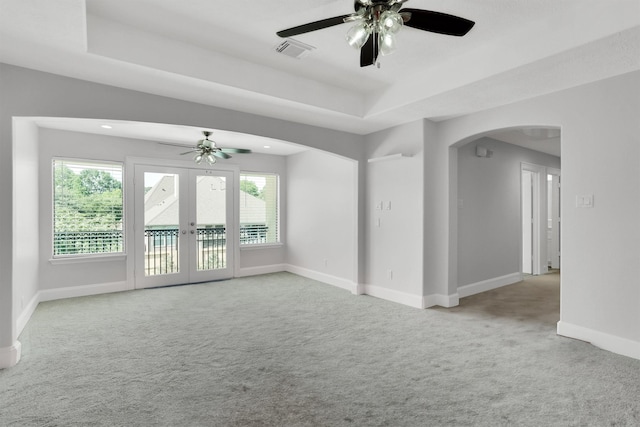 spare room featuring french doors, ceiling fan, light colored carpet, and a healthy amount of sunlight