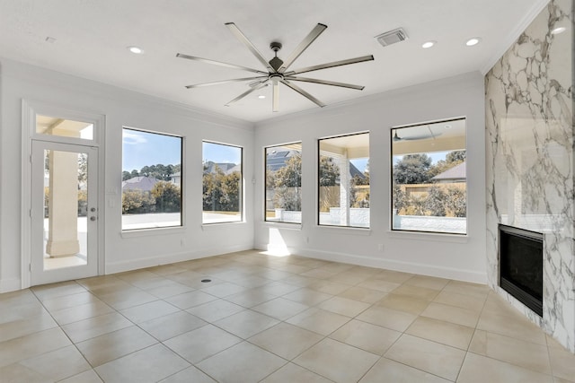 unfurnished living room with crown molding, a healthy amount of sunlight, ceiling fan, and a fireplace