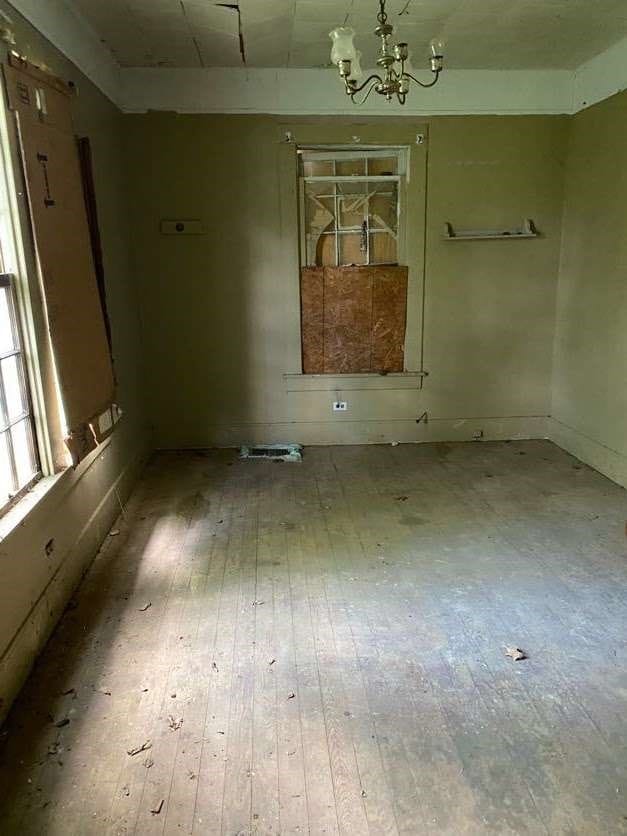 spare room with hardwood / wood-style flooring and a chandelier