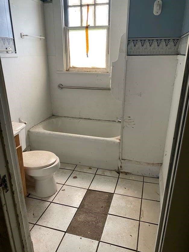 bathroom with a bathtub, toilet, vanity, and tile patterned flooring