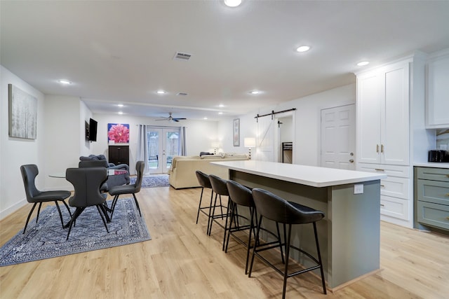 kitchen with a center island, french doors, a barn door, light wood-type flooring, and a breakfast bar area