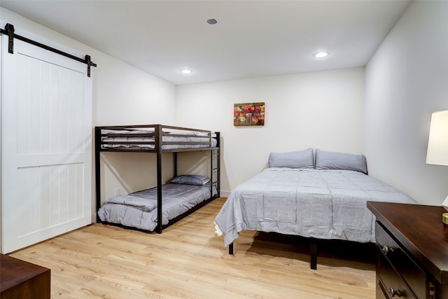 bedroom with a barn door and light hardwood / wood-style flooring