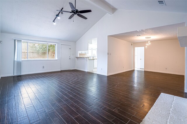 unfurnished living room with dark wood-type flooring, ceiling fan, vaulted ceiling with beams, and a textured ceiling