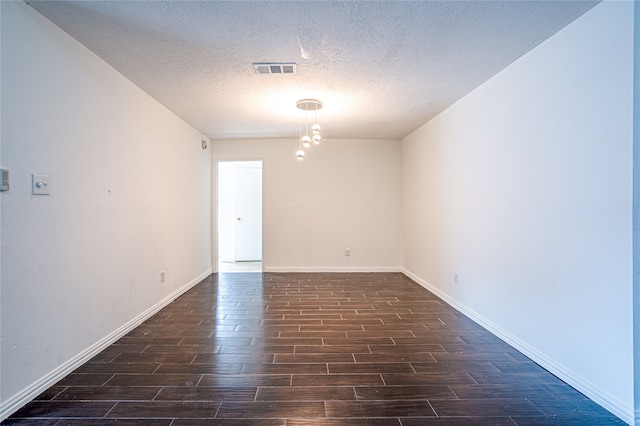 spare room with a textured ceiling and dark wood-type flooring