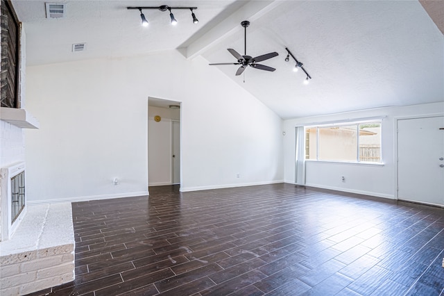 unfurnished living room with a textured ceiling, dark wood-type flooring, a brick fireplace, lofted ceiling with beams, and ceiling fan