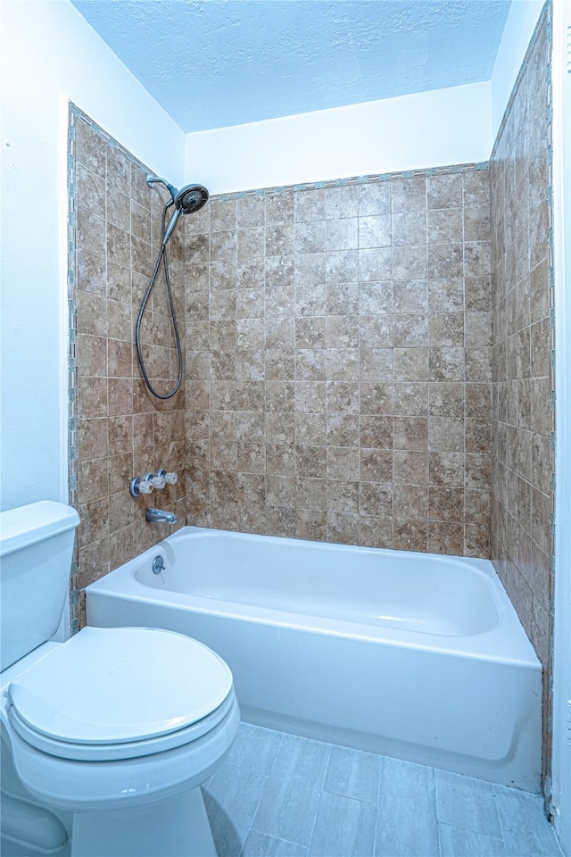 bathroom featuring tiled shower / bath combo, toilet, and a textured ceiling