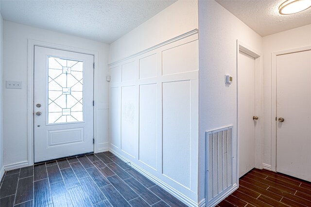 entryway featuring a textured ceiling and dark hardwood / wood-style flooring