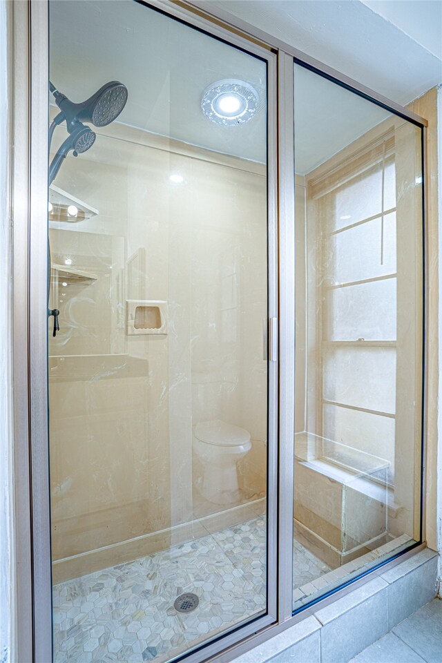 bathroom with toilet, an enclosed shower, and tile patterned flooring