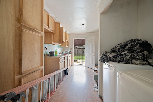 clothes washing area with ornamental molding, light hardwood / wood-style flooring, and separate washer and dryer