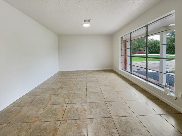 tiled empty room featuring a textured ceiling