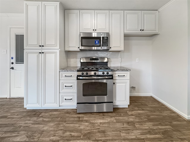 kitchen with crown molding, stainless steel appliances, and light stone countertops