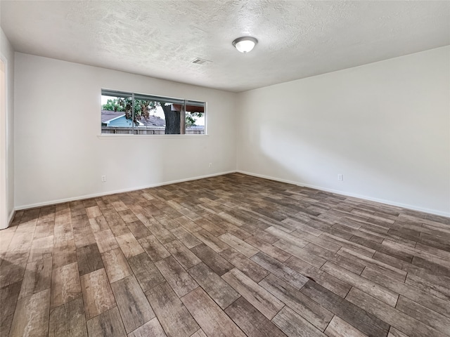 spare room featuring dark hardwood / wood-style floors and a textured ceiling