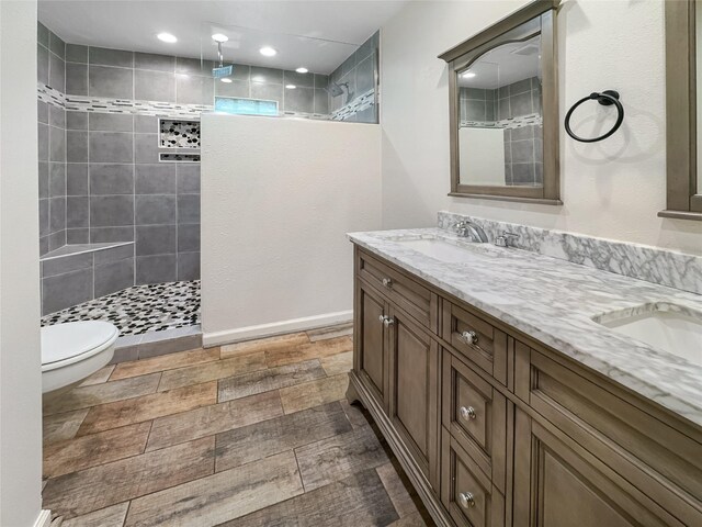 bathroom featuring tiled shower, vanity, and toilet