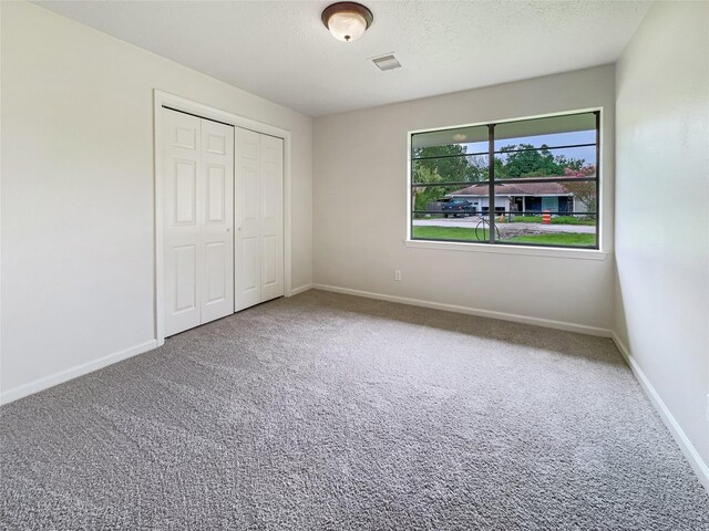 unfurnished bedroom with a closet, a textured ceiling, and carpet floors