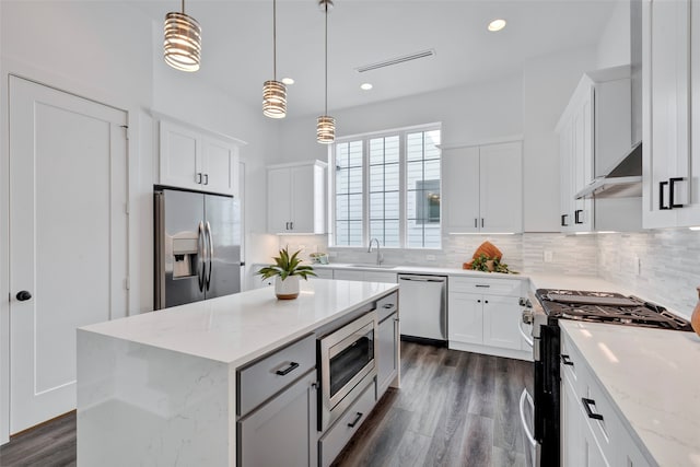 kitchen featuring pendant lighting, white cabinetry, a kitchen island, light stone counters, and appliances with stainless steel finishes