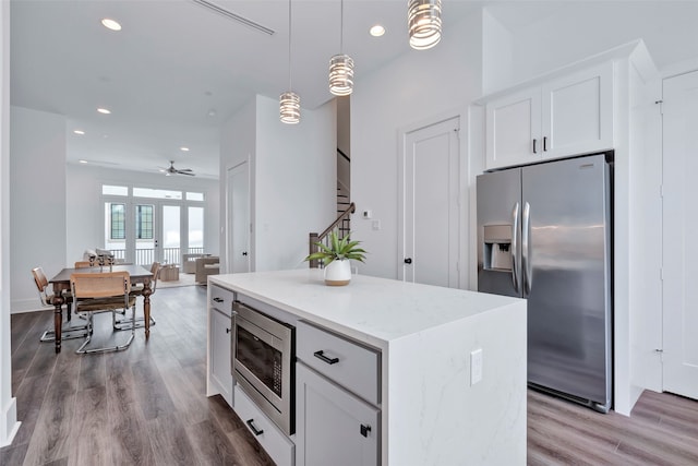 kitchen with light hardwood / wood-style flooring, light stone countertops, appliances with stainless steel finishes, and white cabinetry