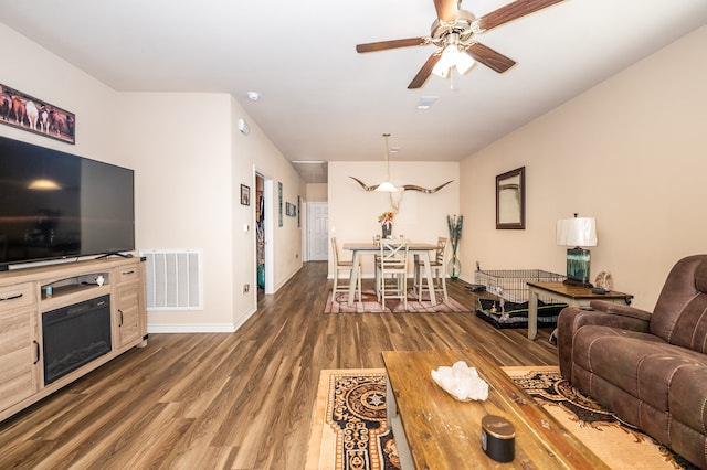 living room with dark wood-type flooring and ceiling fan