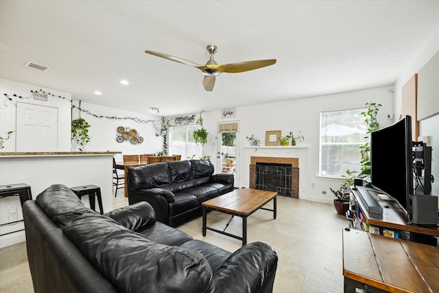 living room featuring ceiling fan, a fireplace, and plenty of natural light