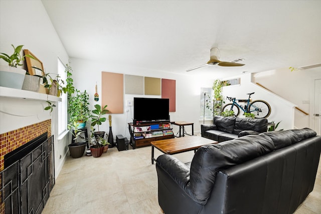 living room with ceiling fan and a tile fireplace