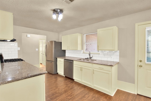 kitchen with dark stone countertops, stainless steel appliances, dark hardwood / wood-style flooring, sink, and tasteful backsplash