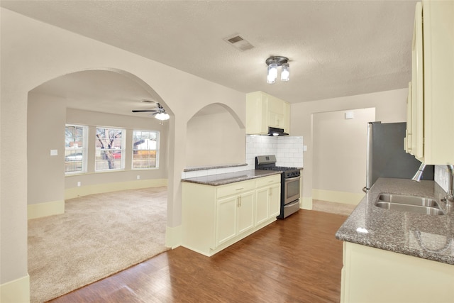 kitchen with dark stone countertops, stainless steel appliances, sink, ceiling fan, and dark wood-type flooring