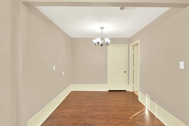 unfurnished dining area with wood-type flooring, an inviting chandelier, and a textured ceiling