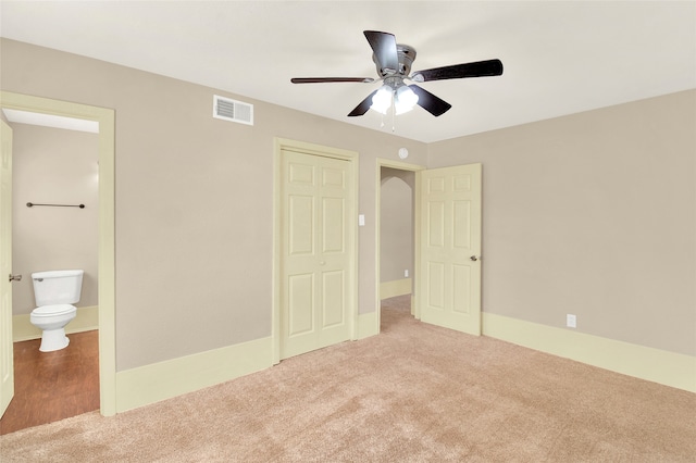 unfurnished bedroom with carpet, ceiling fan, a closet, and ensuite bath