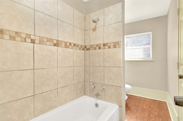 bathroom featuring wood-type flooring, toilet, and tiled shower / bath