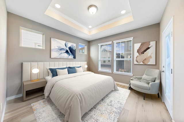 bedroom with a tray ceiling, light hardwood / wood-style floors, and crown molding