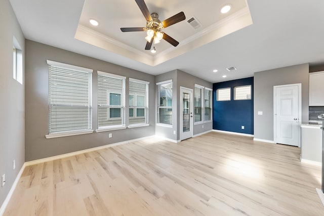 unfurnished living room with ceiling fan, a tray ceiling, and light hardwood / wood-style floors