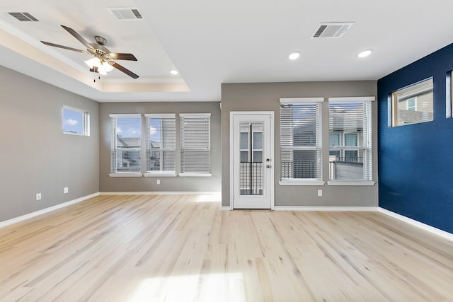 unfurnished living room featuring crown molding, a raised ceiling, light hardwood / wood-style flooring, and ceiling fan