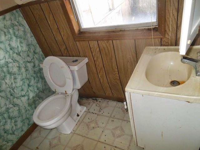 bathroom with vanity, toilet, and wood walls