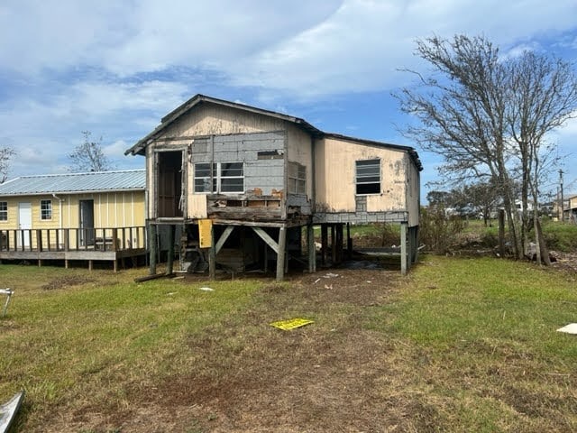 rear view of house featuring a wooden deck and a lawn