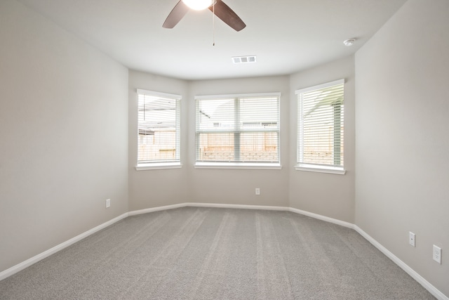 carpeted spare room featuring plenty of natural light and ceiling fan