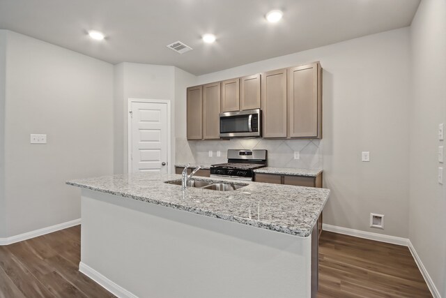 kitchen featuring stainless steel appliances, sink, an island with sink, dark wood-type flooring, and decorative backsplash